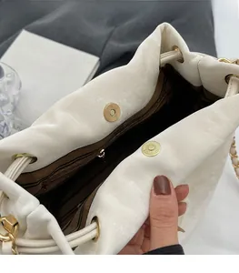Detail view of cream drawstring bucket bag with gold magnetic closure and striped lining