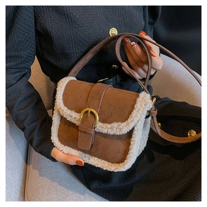 Détail du sac bandoulière en daim marron avec bordure en polaire et boucle dorée