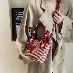 Elegant red tweed bucket bag with heart scarf handle and cute puppy charm on a stylish model