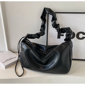 Detail of black pleated PU leather shoulder bag with wide strap and metallic zipper