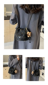Detail of black pebbled leather bucket bag with silver chain and brown teddy bear charm