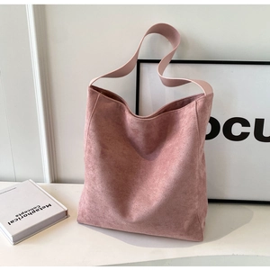 Detail view of pink matte suede tote bag featuring a wide shoulder strap and minimal design