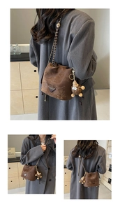 Detailed view of dark brown bucket bag with chain strap and soft plush doll accessory
