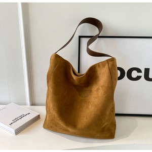 Detail of caramel suede hobo bag with textured fabric and wide leather shoulder strap