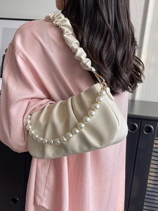 Schicke plissierte Cloud-Bag mit Perlenkette in Creme-Weiß, von einem Model getragen