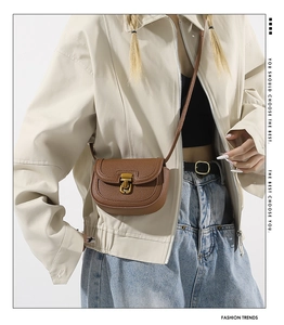 Brown lychee leather saddle bag with vintage gold buckle shown on a female model