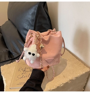 Close-up of pink bucket bag with gold chain strap and cute plush charm pendant