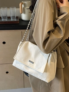 Minimalist beige marble textured shoulder bag with chic chain strap worn by a model