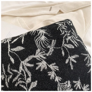 Macro detail of black and white jacquard woven fabric with intricate floral leaf patterns