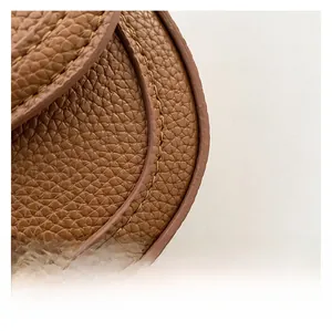 Close-up of brown litchi grain leather texture and handcrafted stitching on the bag