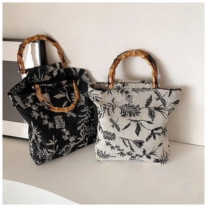 Detailed view of bamboo handles on embroidered canvas tote bags with plant patterns