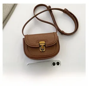 Mini brown saddle bag with retro gold clasp next to a smartphone for size reference