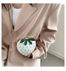 Detail of white strawberry bag with gold rivets and leaf accents on chain strap