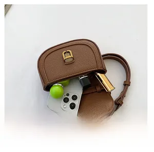 Detail view of brown saddle bag interior capacity with smartphone and lipstick items