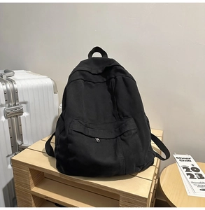 Detailed view of black canvas backpack with front zipper pocket and side water bottle holder