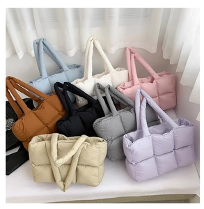 Flat lay view of quilted puffer tote bags in eight assorted colors on white background
