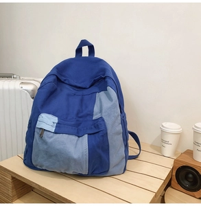 Detail view of a blue patchwork canvas backpack on a wooden surface in a cafe setting