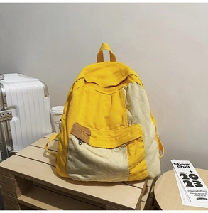 Detail of canvas backpack with contrast yellow and cream panels on a wooden tray