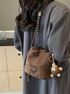 Brown vintage faux leather bucket bag with gold chain strap and plush charm