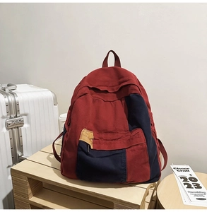 Detail of red and navy color-block canvas backpack displayed on a wooden tray