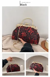 Close-up of black silk handbag with red floral embroidery and gold metal chain strap