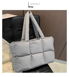 Detail view of the quilted grey down tote bag with wide straps on a black chair
