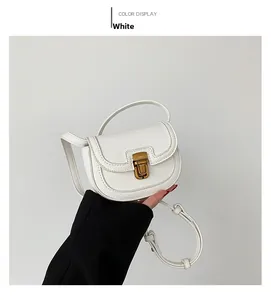Detail of white grained leather mini saddle bag with vintage gold metal clasp hardware