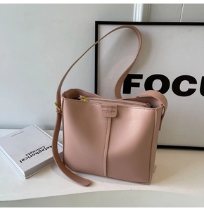 Detail of nude pink leather bucket bag with top metal zipper and fine vertical stitching