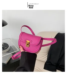 Detail of rose red saddle bag with lychee texture leather and gold metal buckle