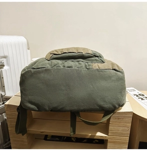 Close-up of the wide拼接canvas base of the olive green and khaki outdoor backpack