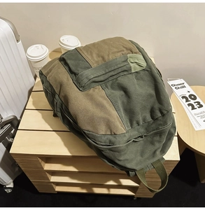 Detail shot of the army green and coffee canvas backpack on a wooden table setup