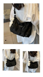 Detail der schwarzen Samt-Tragetasche mit Mode-Etikett und weißem Plüschbär-Anhänger