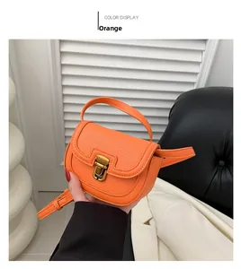 Detail of orange pebble leather saddle bag with gold metal clasp and top handle