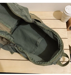 Detail view of the green canvas backpack interior showing the main pocket and smooth zipper