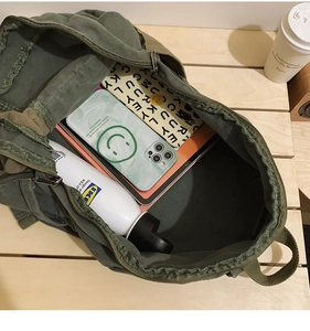 Detail of army green canvas backpack interior showing spacious storage for tablet and bottles