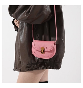 Detailed view of pink pebble leather saddle bag with vintage metal clasp on model