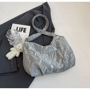 Detail der silbernen Tasche mit Knitteroptik, Modelabel und urbanen Deko-Elementen