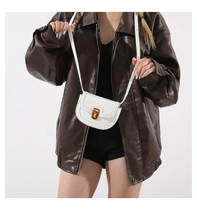 Close-up of a white mini leather saddle bag with vintage gold clasp on a model