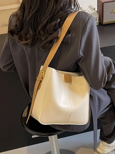 Minimalist cream white women's bucket bag with brown adjustable strap in street style