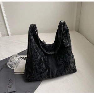Détail du sac cabas plissé noir avec texture riche et design minimaliste de bandoulière