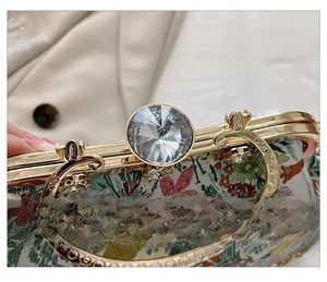 Detail of flower evening bag showing sparkling rhinestone clasp and ornate golden metal handle