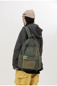 Detailed back view of a person wearing a large olive green canvas backpack with wide straps