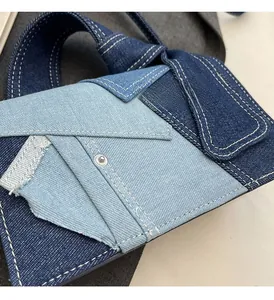 Detailed close-up of blue denim patchwork handbag with white contrast stitching and rivets