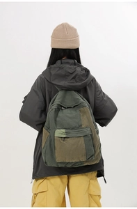 Detail of color-block canvas backpack worn by model showing vintage khaki and green tones
