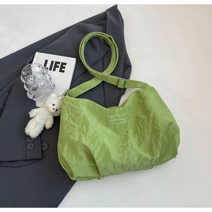 Detail showing light green crinkled fabric tote with adjustable strap and bear charm
