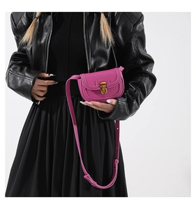 Fuchsia saddle bag with lychee texture leather and gold metal buckle shown on a model