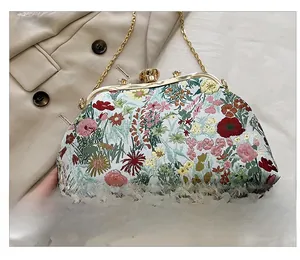 Close-up of vintage floral embroidery on handbag with gold metal clasp and chain