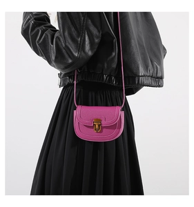 Close-up of fuchsia saddle bag in litchi grain leather with vintage gold metal lock