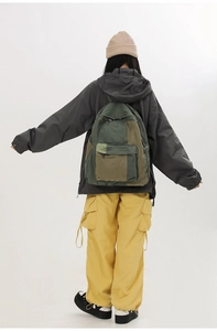 Rear view of a khaki and army green color-block canvas backpack on a female model