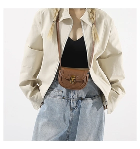 Detail of a brown lychee pattern leather mini saddle bag with vintage brass buckle clasp